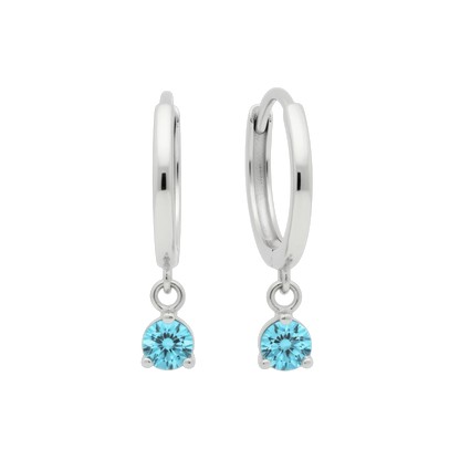 Qutahia Jewelry 14k solid gold dangling huggie earrings with round blue gemstone in claw setting.