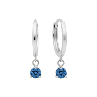 Qutahia Jewelry 14k solid gold dangling huggie earrings with blue zircon gemstone in a claw setting.
