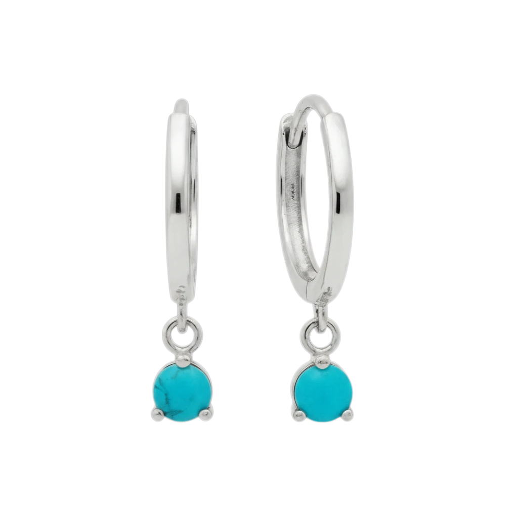 Qutahia Jewelry 14k solid gold huggie earrings with dangling turquoise gemstones in a claw setting.